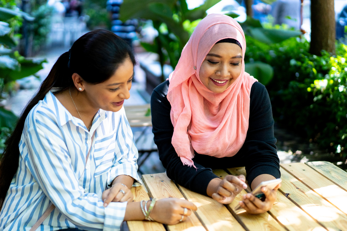 Indian and Malay ethnicity women sharing information with smart phone.